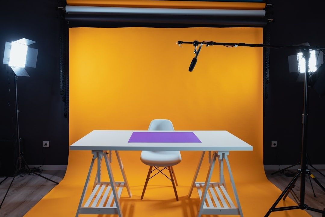 En enkel hemmastudio med skrivbord, orange bakgrund och studiobelysning